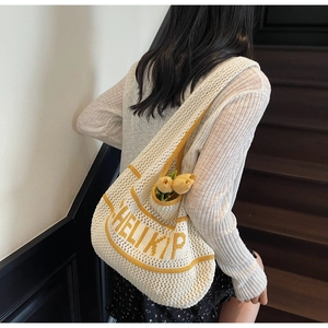 White and yellow knitted tote bag with HELI KIP lettering shown on a model's shoulder