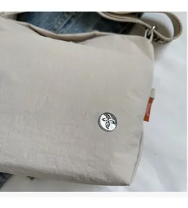 Detail of light beige canvas bag showing texture, silver logo, and orange side label