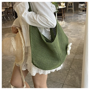 Détail du sac hobo en crochet vert foncé avec fleur blanche dans un style de vacances