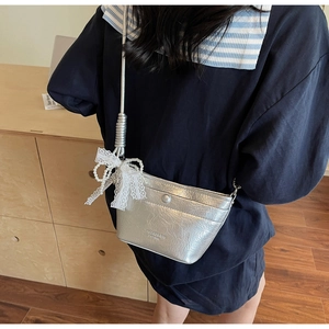 Detail of silver metallic bucket bag featuring lace pearl bow and pleated texture