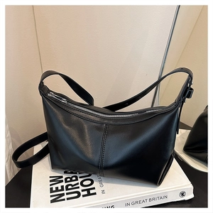 Detailed macro shot of a black minimalist hobo bag with smooth leather texture and silver zipper