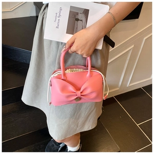 Détail du sac seau rose avec nœud, fermeture à cordon et pendentif cœur doré élégant
