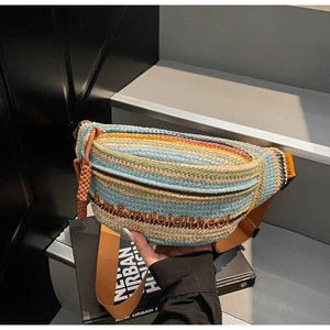 Detailed close-up of a colorful striped woven crossbody bag with embroidery and charm