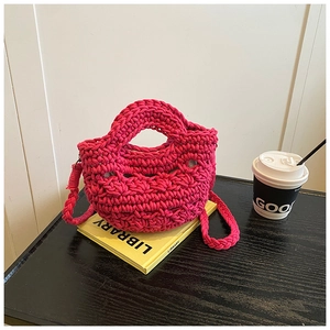 Macro detail of rose red crochet knit bucket bag showing texture on a wooden desk