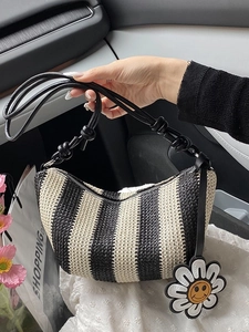 Striped straw hobo bag with a sunflower charm and sleek black leather shoulder strap