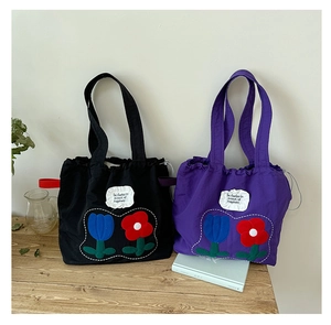 Detail of canvas tote bags in black and purple featuring floral tulip embroidery