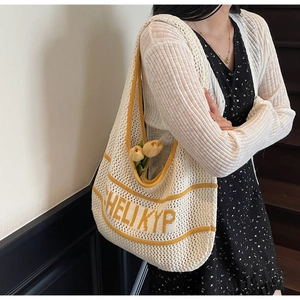 Detail of hand-knit tote bag with yellow stripes and HELI KYP text on beige texture