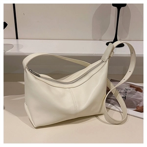 Detail of cream crescent hobo bag featuring smooth faux leather and curved top zipper closure