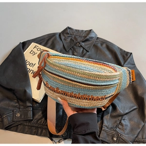 Detail of colorful woven straw bag featuring multi-color stripes and letter embroidery