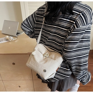 Detail of off-white canvas crossbody bag with striped wide strap and zipper pockets