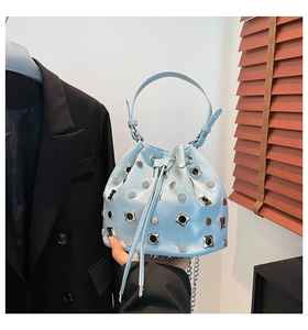 Detail of light blue bucket bag featuring metallic studs, drawstring and silver chain