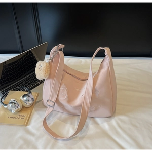 Pink canvas tote bag with bear embroidery, plush charm and laptop on a desk