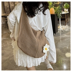 Détail du sac hobo tissé kaki avec une breloque marguerite blanche et texture au crochet