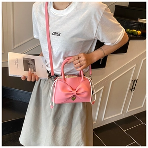 Détail du sac seau rose avec nœud, pendentif en cœur et bandoulière amovible