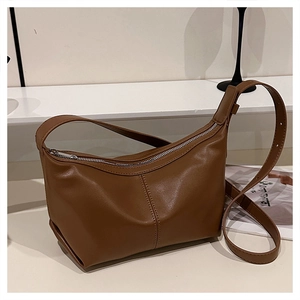 Macro detail of caramel brown leather shoulder bag featuring vertical stitching and silver zipper