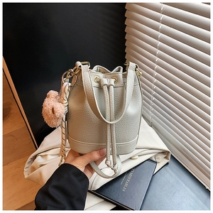 Detail of grey pebbled leather bucket bag with drawstring and plush bear charm