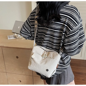 Detail of off-white canvas crossbody bag with dual zippers and patterned wide strap