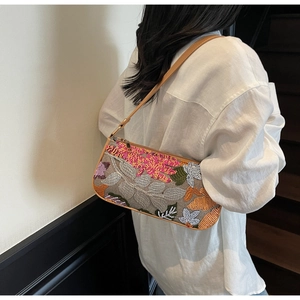 Detail of colorful sequin floral embroidery on retro canvas baguette bag with brown leather strap