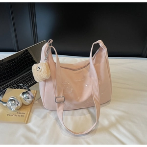 Close-up of pink canvas dumpling bag with cute cat embroidery and teddy bear charm