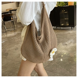 Détail d'un sac cabas tissé avec motif au crochet marron et breloque marguerite