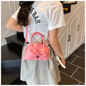 Vue détaillée du sac seau rose à nœud avec pendentif cœur et bandoulière réglable
