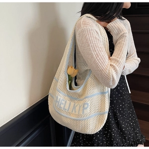 Detail of white knit tote bag with blue stripes and HELI KYP text on shoulder