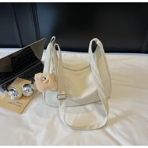 Detail of off-white dumpling crossbody bag with embroidery and plush bear charm