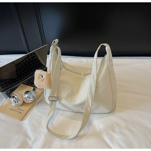 Detail of cream shoulder bag featuring cute cat embroidery and brown plush charm accessory