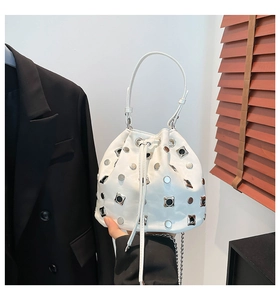 Detail of white leather drawstring bucket bag with silver metal studs and chain strap