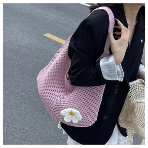 Détail du sac à bandoulière tissé rose avec fleur de marguerite 3D sur texture tricotée