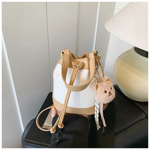 Detail of two-tone bucket bag in white and camel with a cute plush bear charm