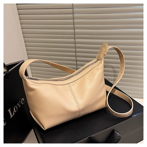Detail view of cream-colored shoulder bag with silver zipper and adjustable strap buckle