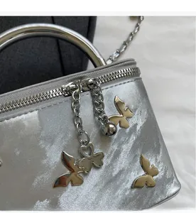 Close-up of silver box bag featuring a smooth zipper and decorative butterfly charm