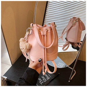 Detail of pink bucket bag with drawstring closure and cute plush bear accessory