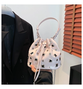 Close-up of pink bucket bag with silver rivets and drawstring closure held by hand