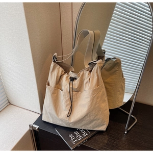 Close-up of khaki drawstring bucket bag with large front pocket and wide strap texture