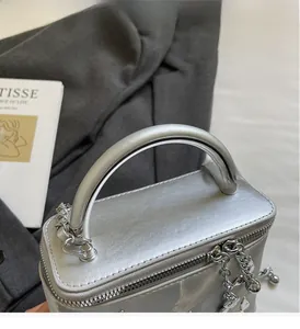 Detailed view of the silver metallic textured box bag with a sturdy curved handle and chain