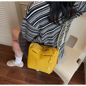 Detailed close-up of yellow nylon crossbody bag with colorful rainbow wide shoulder strap