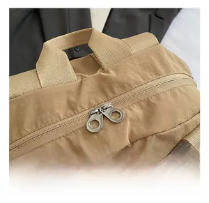 Detail showing smooth dual metal zippers and durable woven handle on khaki backpack