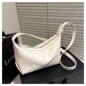 Detailed view of cream leather shoulder bag with zipper closure on black display box