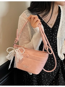 Pink pleated shoulder bag featuring white lace bow and pearl charm worn by a model