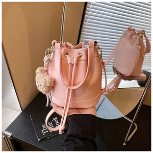 Detail of pink pebbled leather bucket bag with cute bear charm and drawstring closure