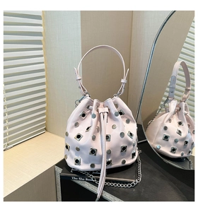 Detail of light pink bucket bag with silver metal studs and drawstring closure