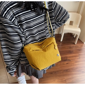 Detail of a bright yellow canvas crossbody bag with wide patterned strap and dual zippers