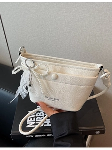 Chic cream-white bucket crossbody bag with pearl bow and lace charm detail