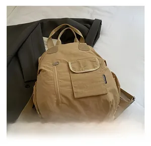 Detail view of khaki multifunctional travel backpack with metal snap pocket and sturdy handle
