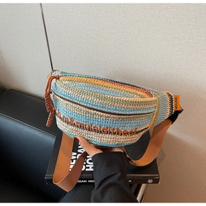 Detail of colorful woven straw bag featuring striped design and adjustable nylon shoulder strap