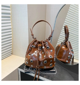 Macro detail of brown leather bucket bag with silver metal studs and chic drawstring