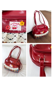 Close-up of red bowling bag with floral lace trim, cherry embroidery, and plaid fabric detail