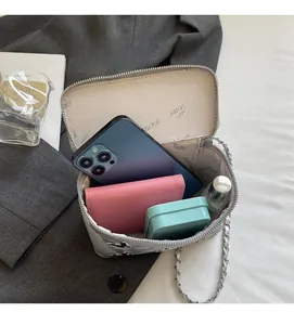 Interior view of small silver box bag showing capacity for phone and perfume bottle
